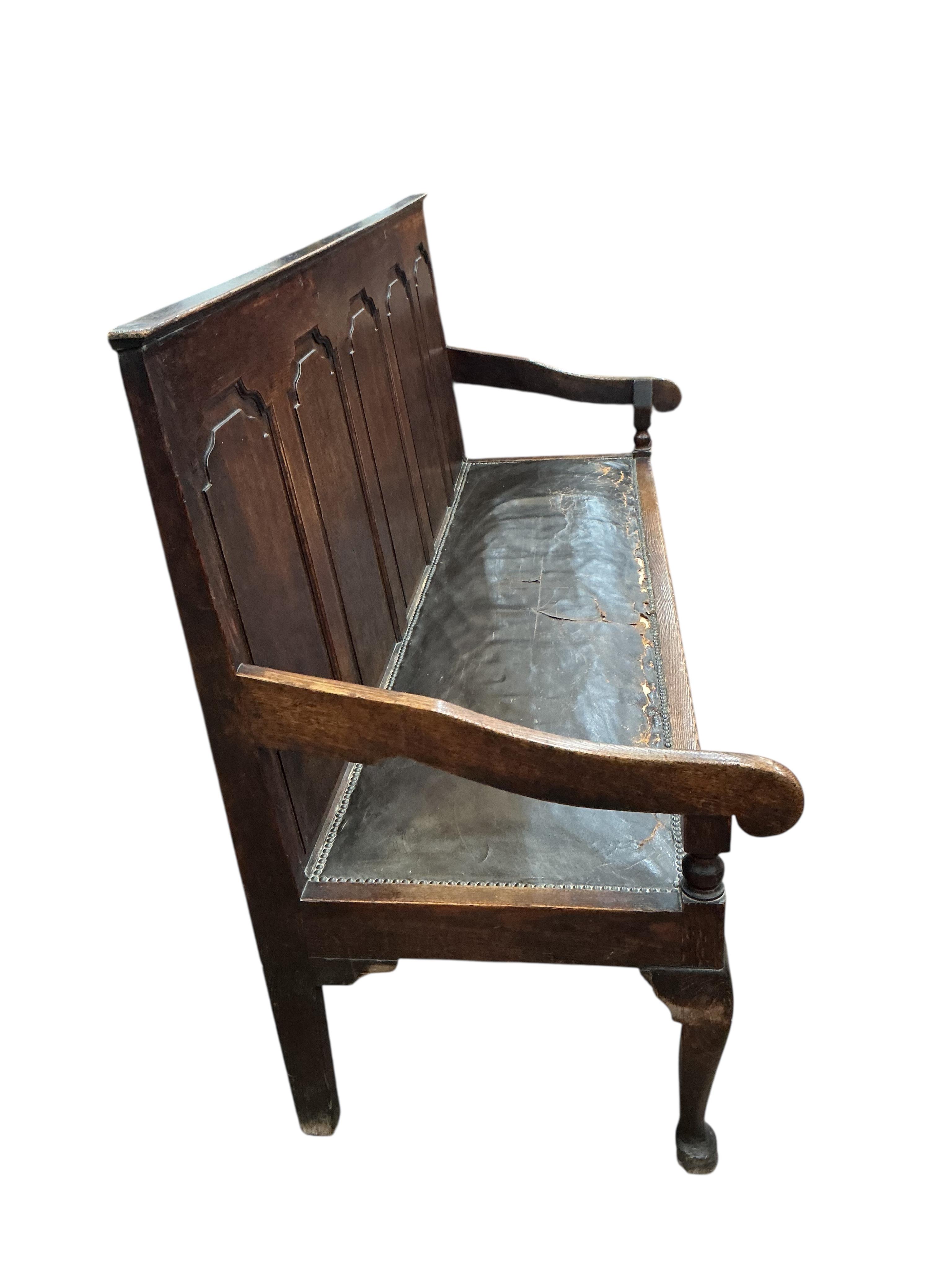 A George III panelled oak settle on cabriole front legs, width 185cm, depth 65cm, height 106cm